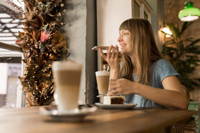 Cheerful woman talking on phone in cafe