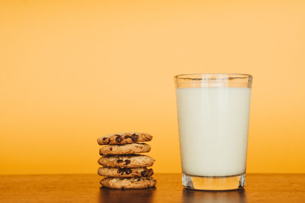 Delicious Breakfast: Cookies and Milk on a Wooden Table with an Orange Background.