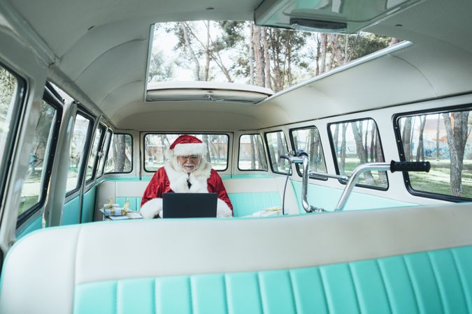 Santa Claus working at laptop in van