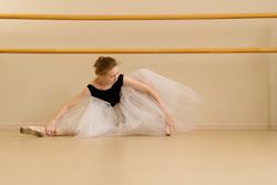 Ballet dancer stretches gracefully in serene dance studio environment.