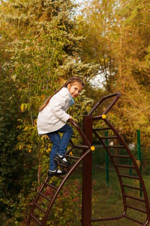 Young girl climbing playground stairs in park