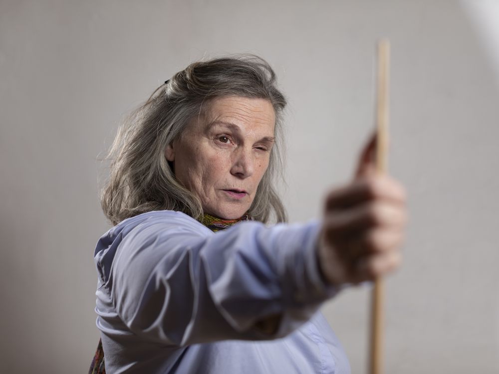 Mature artist woman eye measuring with on of her brushes