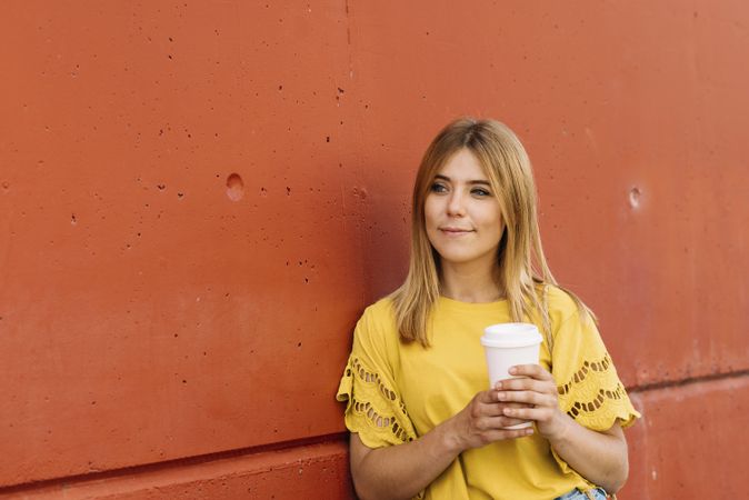 Young blonde woman drinking takeaway coffee