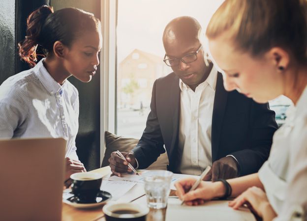 Multi-ethnic group working on business documents in a cafe