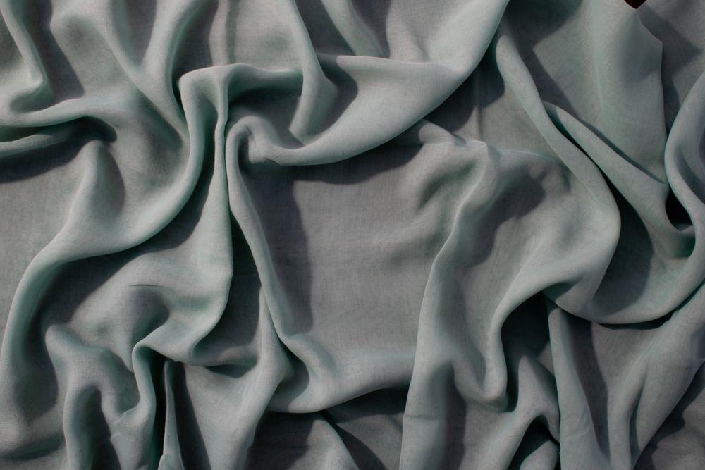Nude green fabric wavy crumpled background texture with copy space.
