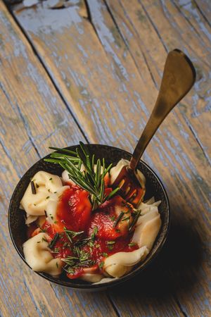 Plate of delicious ravioli with tomato sauce served on table