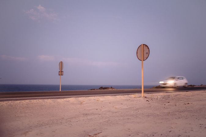 Car moving on road with signs along sea