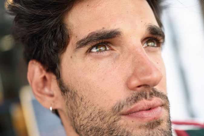 Portrait of dark haired man's face outside