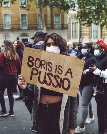 London, England, United Kingdom - June 6th, 2020: Woman in mask with sign disparaging politician