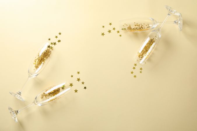 Champagne glasses with glitter on beige background, space for text