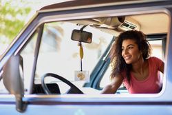 Female in pink t-shirt with curly hair sitting up in passenger side of vehicle