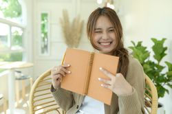Smiling woman holding a book and smiling at the camera.
