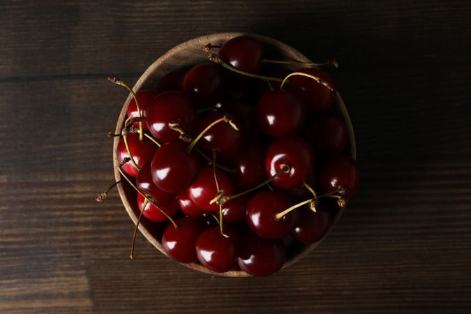 Ripe cherry fruits in a bowl on a wooden background