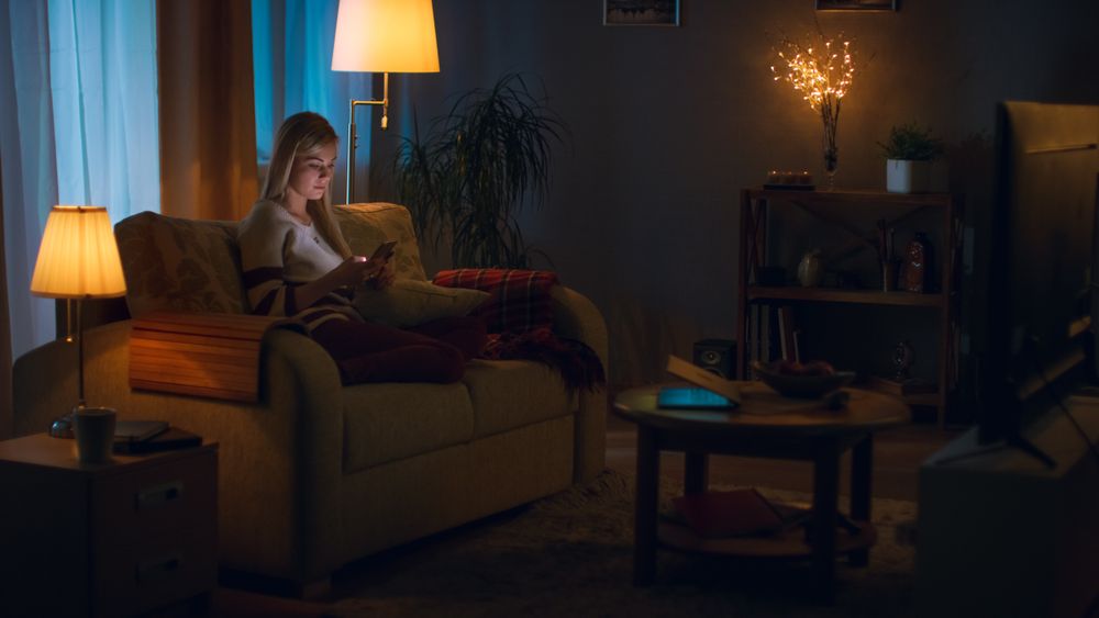 In the Evening Young Woman Relaxes on a Couch in Her Cozy Living Room.
