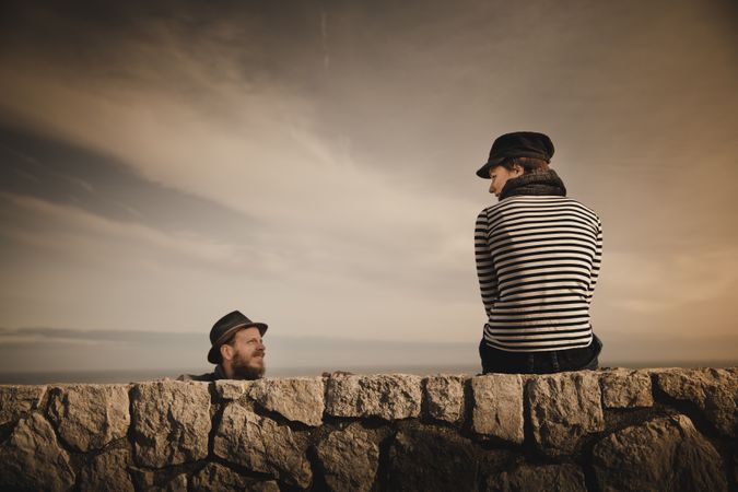 Man and woman leaning out from stones