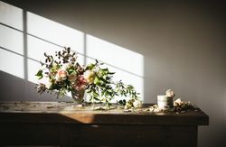 plate with cake decorated flower on table with bouquet of blooms in vase