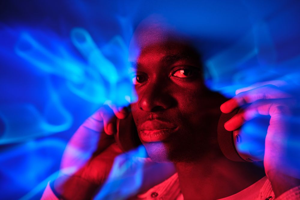Serious Black man in headphones in colorful illumination