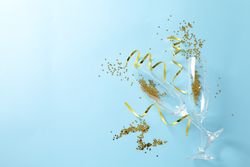 Champagne glasses with glitter on blue background, space for text