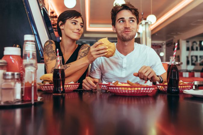 Woman feeding burger to her boyfriend at a restaurant
