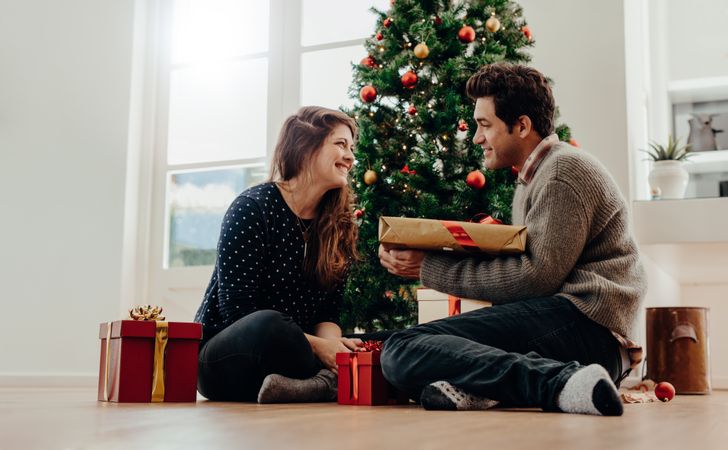 Man and woman exchanging Christmas gifts at home