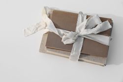 Stack of three old, vintage books tied up with beige ribbon with linen hard cover