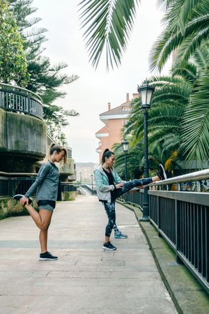 Women runners stretching legs before training