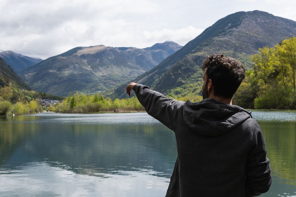 Carefree traveling man enjoying freedom near lake in mountains