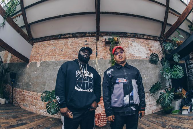 Fisheye wide angle up shot of two Black men standing against industrial exposed brick wall