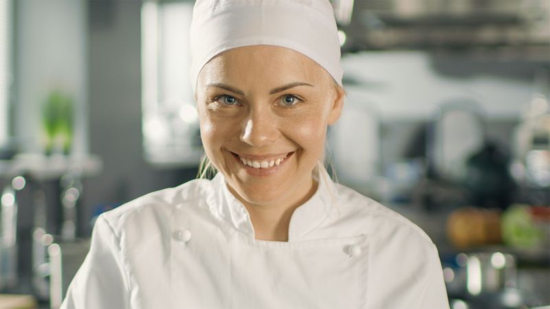 Portrait of a Young Woman Chef Smiling While Cooking in a Modern Kitchen.