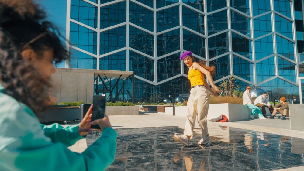 Vibrant Urban Dance Scene With A Young Woman In A Purple Beanie And Yellow Top Performing A Dynamic Dance Move