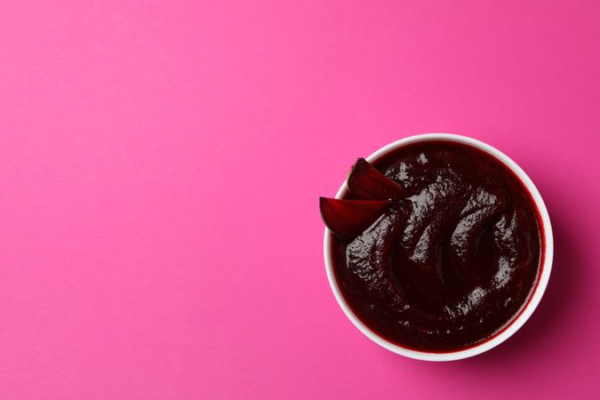 Looking down at bowl of borscht or beetroot soup on pink table with copy space