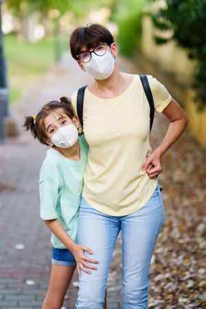 Mother and daughter standing outside together wearing protective masks