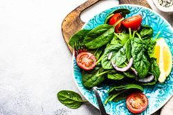 Looking down at leafy spinach salad with lemon slice