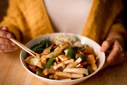 Female eating bowl of cooked appetizing diet dish