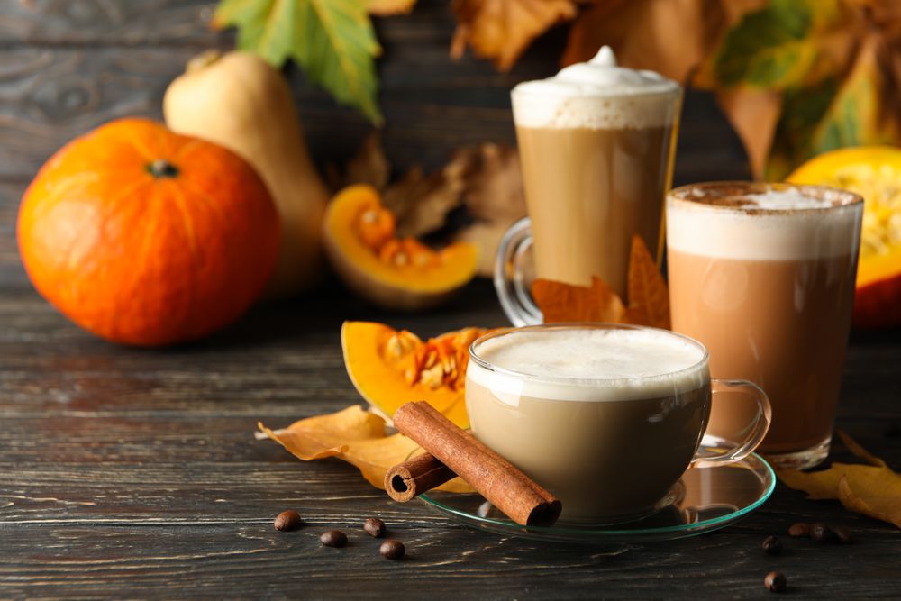 Composition with pumpkin latte, cinnamon and pumpkin on wooden background