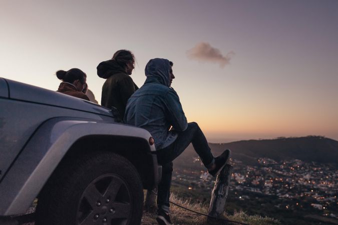Friends on a highway trip enjoying the evening scene of city from a hilltop