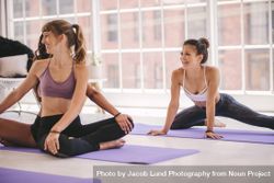 Three young women doing stretching workout and smiling at yoga class 5zYeN0