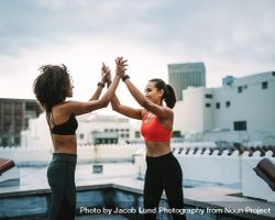 Two fitness women celebrating by giving high five after workout bxLaMb
