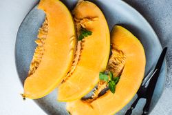 Slices of orange melon laid on plate with fork