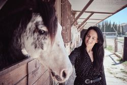 Woman stroking horse in stall