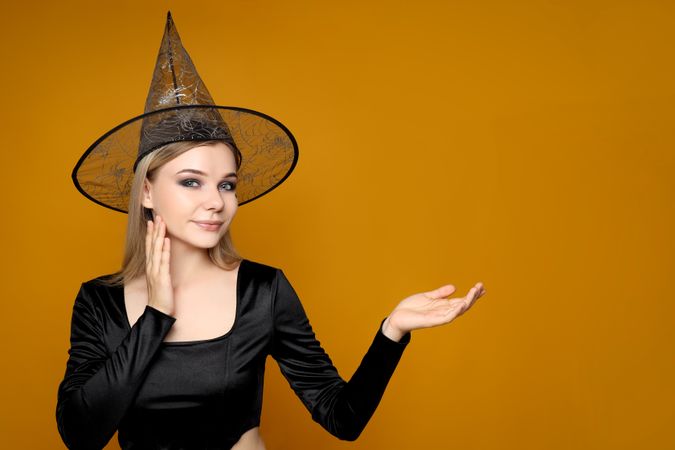 Concept of Halloween, young woman on yellow background