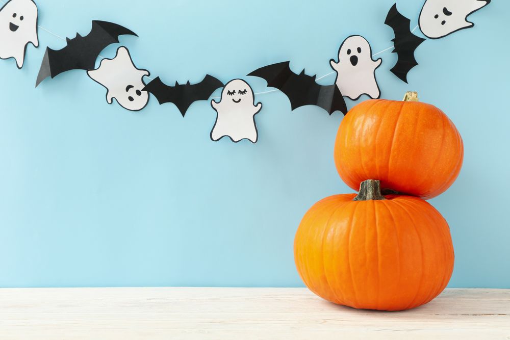 Pumpkins, paper ghosts and bats on blue background
