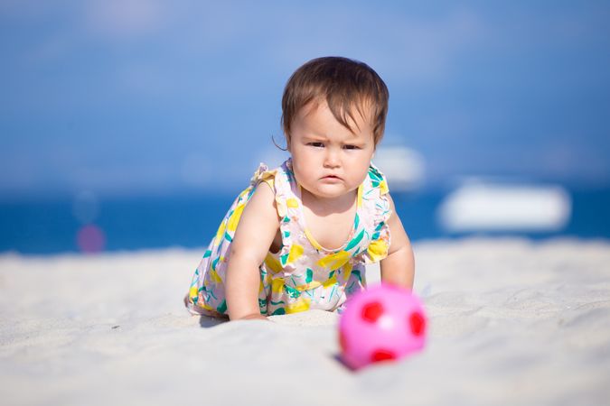 Baby girl playing with ball on beach