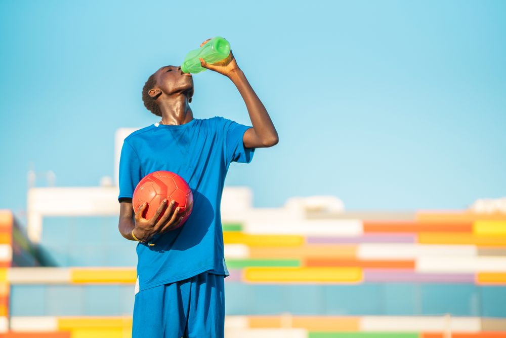Black football player drinking water