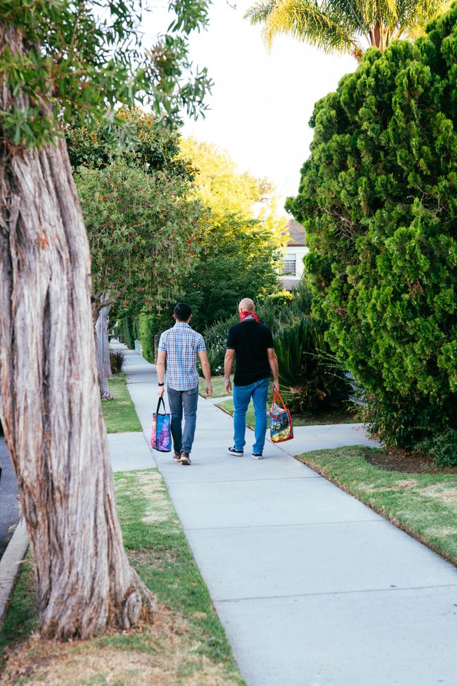 Two men walking down the street carry groceries