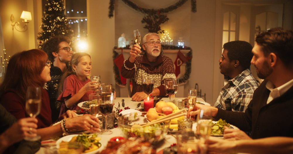 Parents, Children and Friends Enjoying Christmas Dinner Together in a Cozy Home in the Evening.