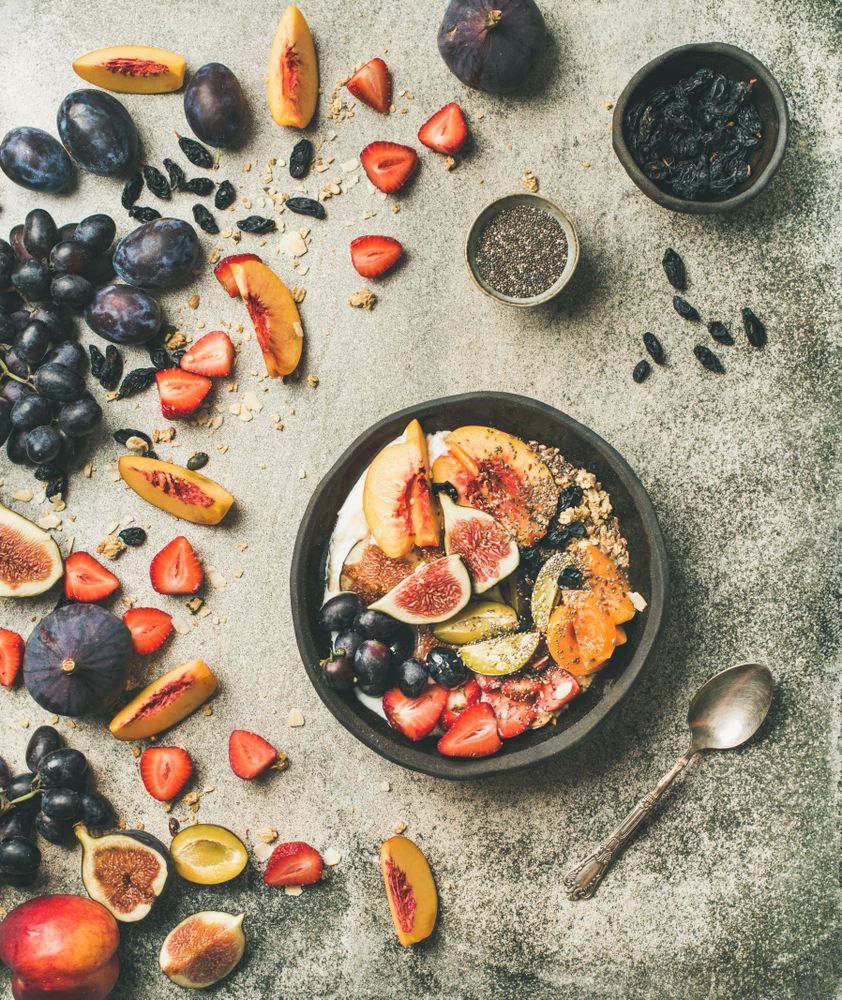 Bowl of yogurt on table with figs, peaches, and chia seeds, square crop