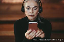 Close up of older woman  listening on phone with headphones 56RRl5