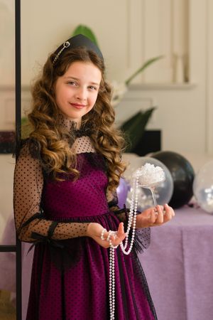 Girl holding pearls and smiling at birthday celebration.