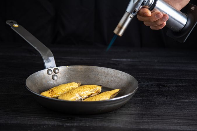 Person cooking endive with burner in pan